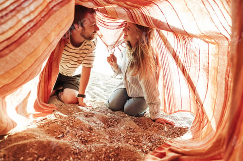 Preview: Happy loving couple outside at the beach under blanket