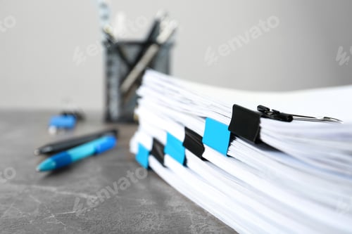 Preview: Stack of documents with binder clips on grey stone table, closeup view. Space for text