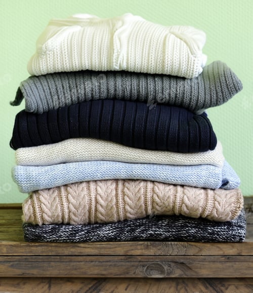 Preview: stack of knitted warm sweaters on a shelf