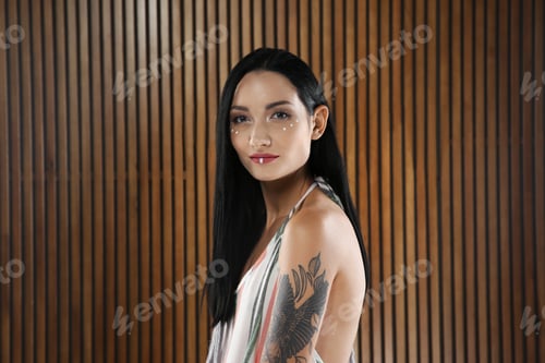 Preview: Portrait of young hippie woman with boho makeup in stylish outfit on wooden background