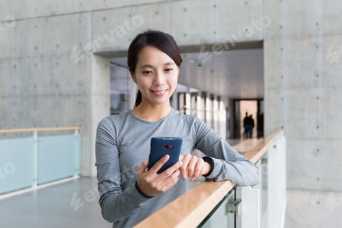 Preview: Woman checking the text message outside office
