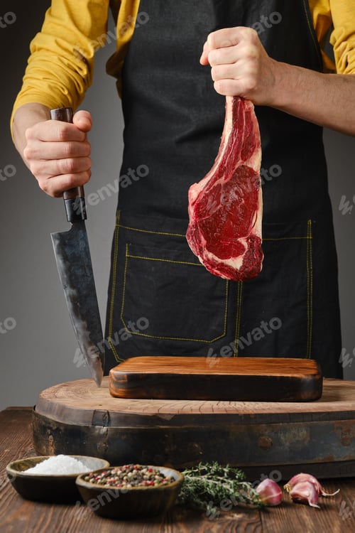Preview: A person in a yellow shirt and apron holds a large cut of raw meat in a rustic kitchen setting