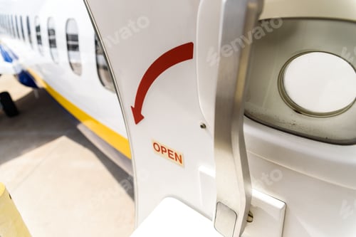 Preview: Open door of a plane parked while passengers disembark.