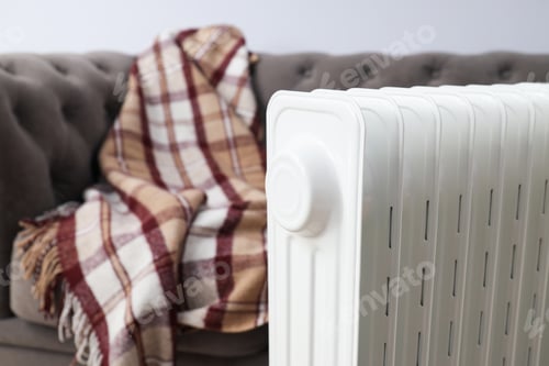 Preview: Concept of heating season, modern electric heater near sofa