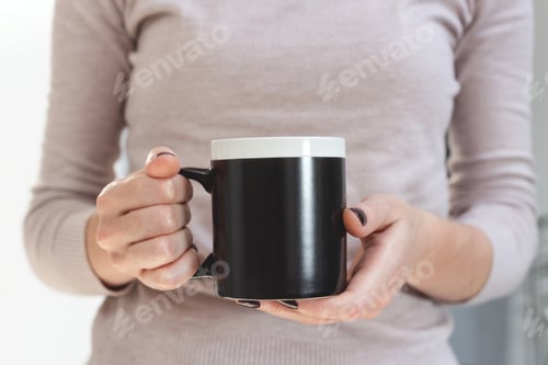 Preview: Black coffee mug mockup for design demonstration. Stylish cup mock up in female hands.