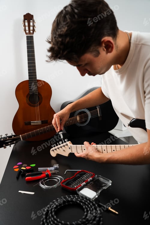 Preview: Musician adjusts guitar headstock tuning pegs with screwdriver