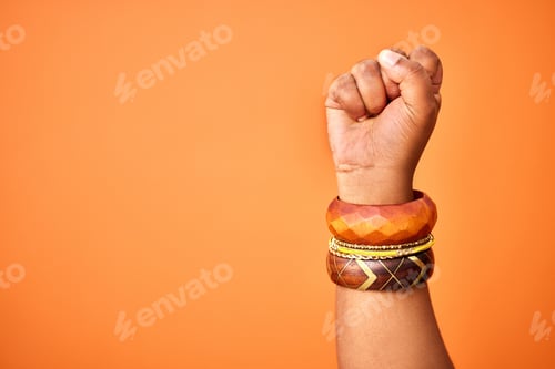 Preview: Shot of an unrecognizable person holding up a fist against an orange background