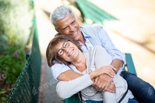 Preview: happy older man and woman hugging on park bench