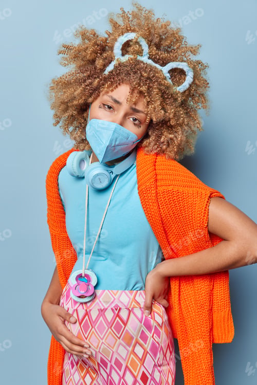 Preview: Vertical shot of sad pregnant woman touches belly feels pain being infected with coronavirus wears p