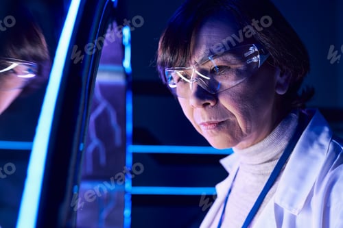 Preview: portrait of middle-aged woman scientist in goggles near new device in futuristic discovery center