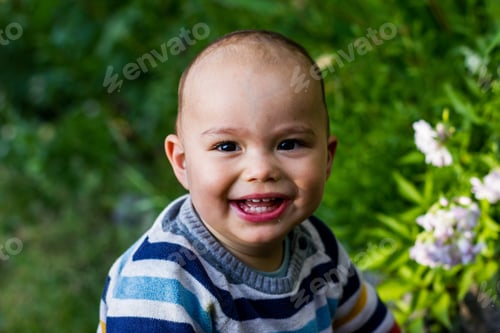 Preview: Cute little baby boy outdoors. Happy smiling baby at green garden.