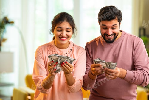Preview: Happy Indian couple holding and showing rupee notes, symbolizing unexpected financial success
