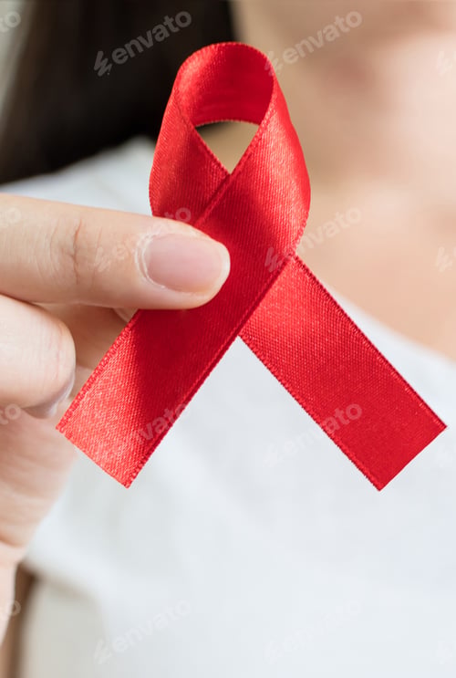 Preview: Closeup shot of a young woman holding a red ribbon - world AIDS day concept