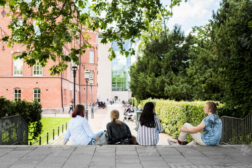 Preview: Students sitting on stairs outside library during study session.