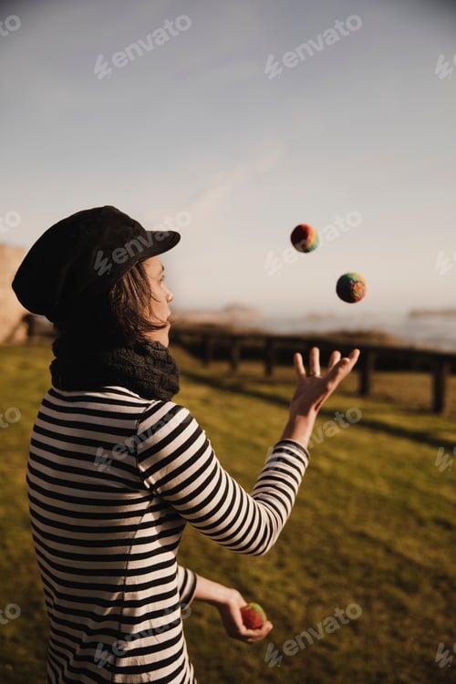 Preview: Woman juggling balls on meadow on shore