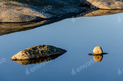 Preview: Closeup shot of the rocks in the pure blue transparent water of the lake
