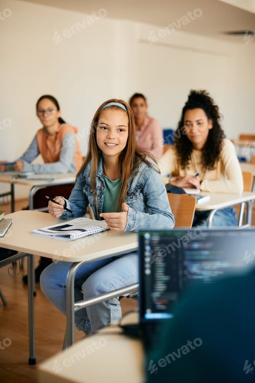 Preview: Happy high school student talking to her teacher during lecture in the classroom.