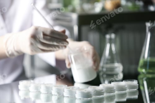 Preview: Scientist working in cosmetic laboratory, focus on jars with cream