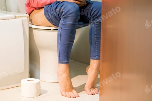 Preview: Cropped image of woman shitting in the toilet consulting the mobile phone