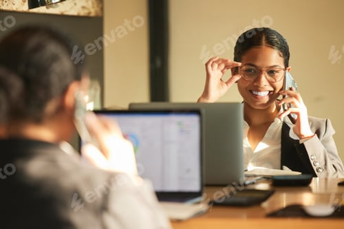 Preview: Shot of a young businesswoman using a laptop while looking in the mirror at work
