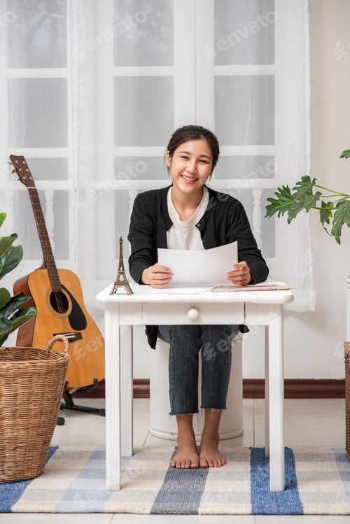 Preview: A woman sitting happily at the desk analyzes documents.