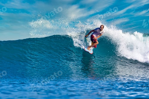 Preview: Male surfer on a blue wave at sunny day