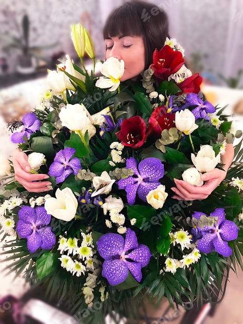 Preview: Young woman enjoying the fragrance of huge beautiful bouquet of flowers