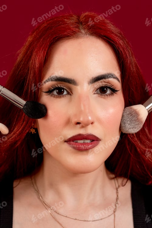 Preview: Stylish woman holding make-up brushes while posing against an isolated background.