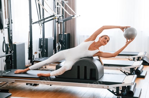 Preview: Holding ball in hands. Young woman in fitness center is doing exercises