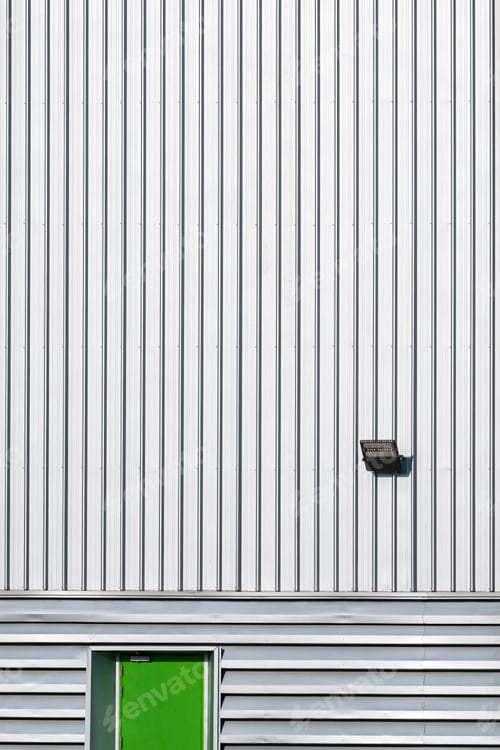 Preview: green steel door with LED spotlight solar power on corrugated metal wall of industrial building