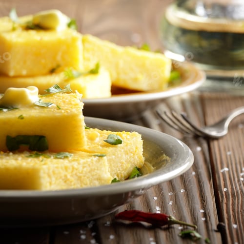 Preview: Polenta with butter and greens on clay dish on wooden rustic tab