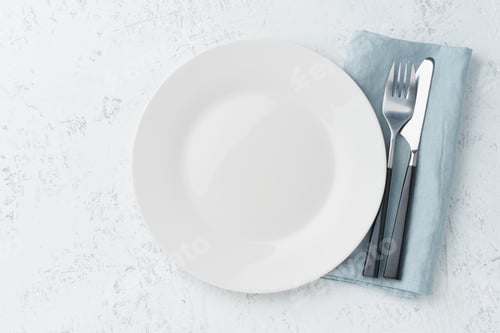 Preview: clean empty white plate, fork and knife on white stone table, copy space, mock up, top view.