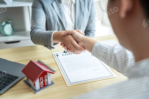 Preview: Estate agent and customers shaking hands together celebrating finished contract after signing