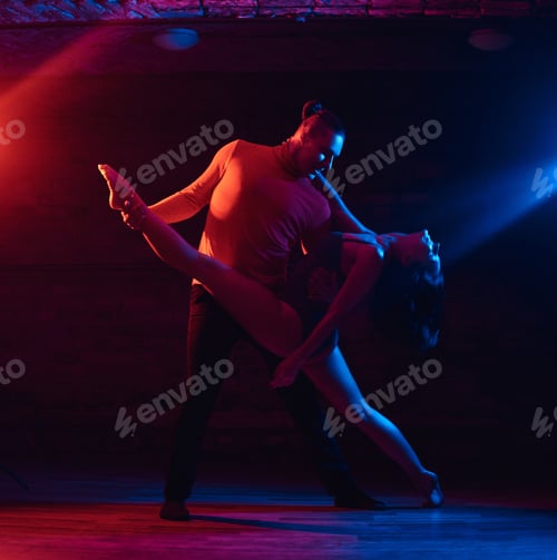 Preview: Beautiful couple dancing in a night club. Dancers performing in the dark with illumination
