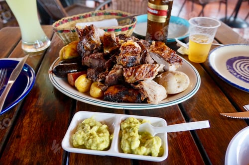 Preview: Churrasco style BBQ meats plated on a table with drinks.