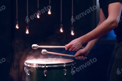 Preview: The drummer plays with mallets on floor tom in dark room.