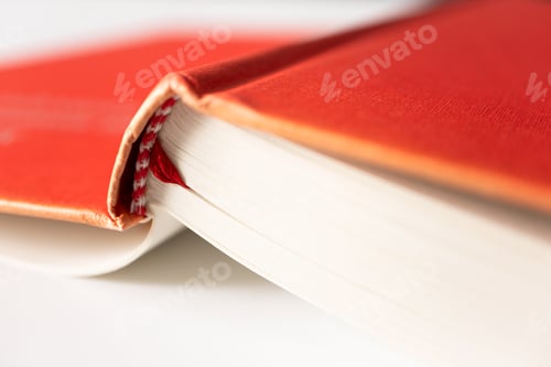Preview: Close-up open book in red cover with selective focus on white background