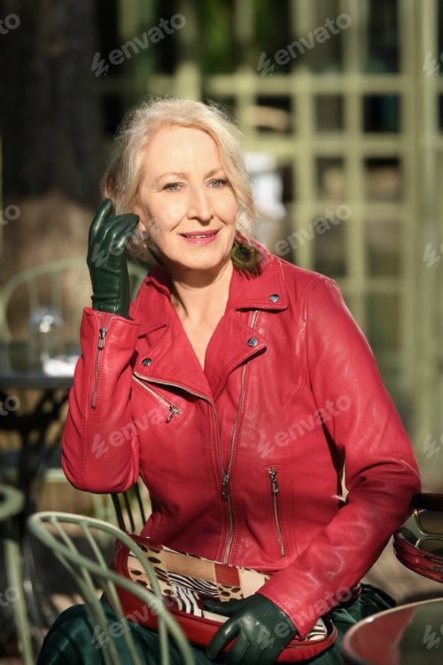 Preview: Gray-haired woman in her sixties in a red leather jacket in a restaurant in the city