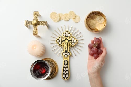 Preview: Bread, cup of wine, grapes in hand, candle and cross on white background, top view