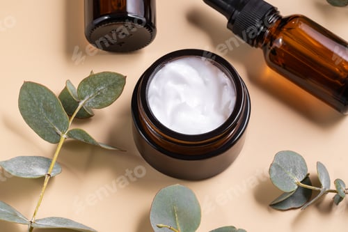 Preview: brown glass cream jar on beige background with eucalyptus branch. Skin care cosmetic concept.