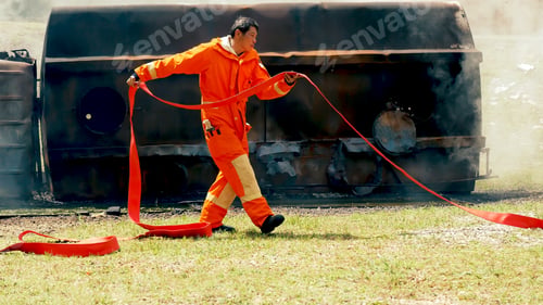 Preview: Firefighter fighting with flame using fire hose chemical water foam spray engine. Fireman hard hat