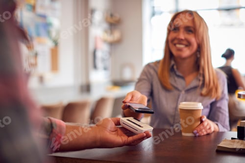 Preview: Female Customer Making Contactless Payment In Coffee Shop Using Mobile Phone