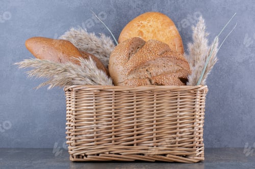 Preview: Basket of bread loaves and feather grass stalks on marble background