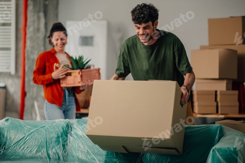 Preview: Couple moving into new apartment carrying boxes and plants