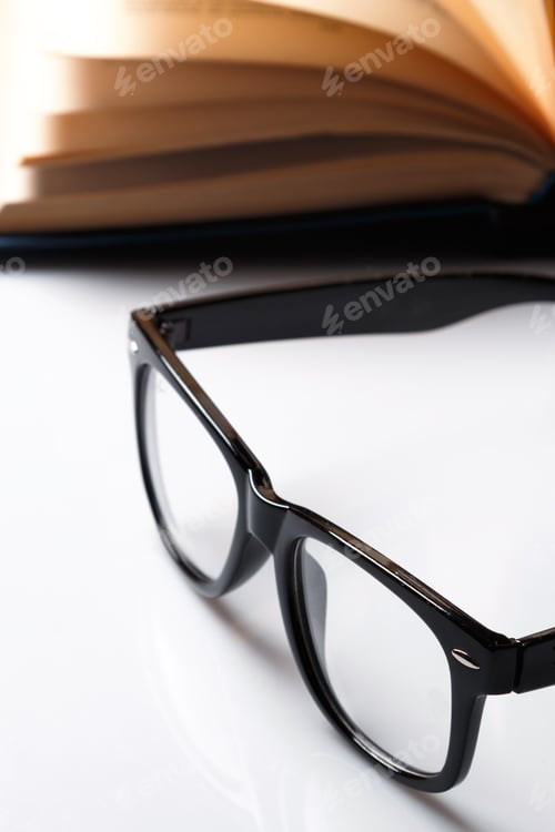 Preview: Open Book and Black Framed Glasses on Table