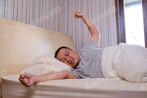 Preview: Man Stretching Arms While Lying in Bed