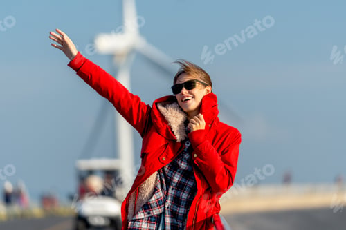 Preview: Caucasian waman with sunglasses stand on the road in front of wind turbine or windmill and happy