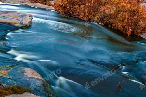 Preview: Stream runs among white wet stones covered with grass in golden autumn