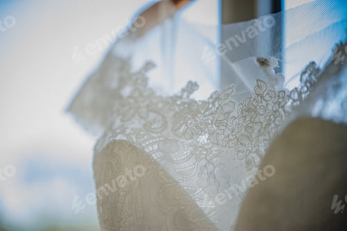 Preview: Closeup of a lace wedding dress hanging in bride's room