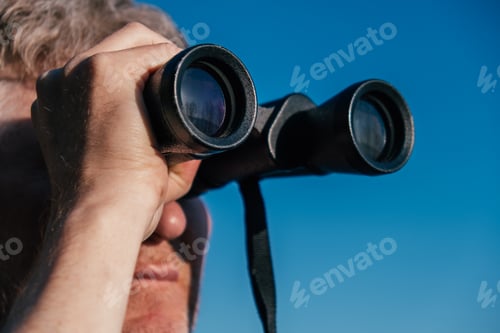 Preview: A man looks through binoculars. Close-up.